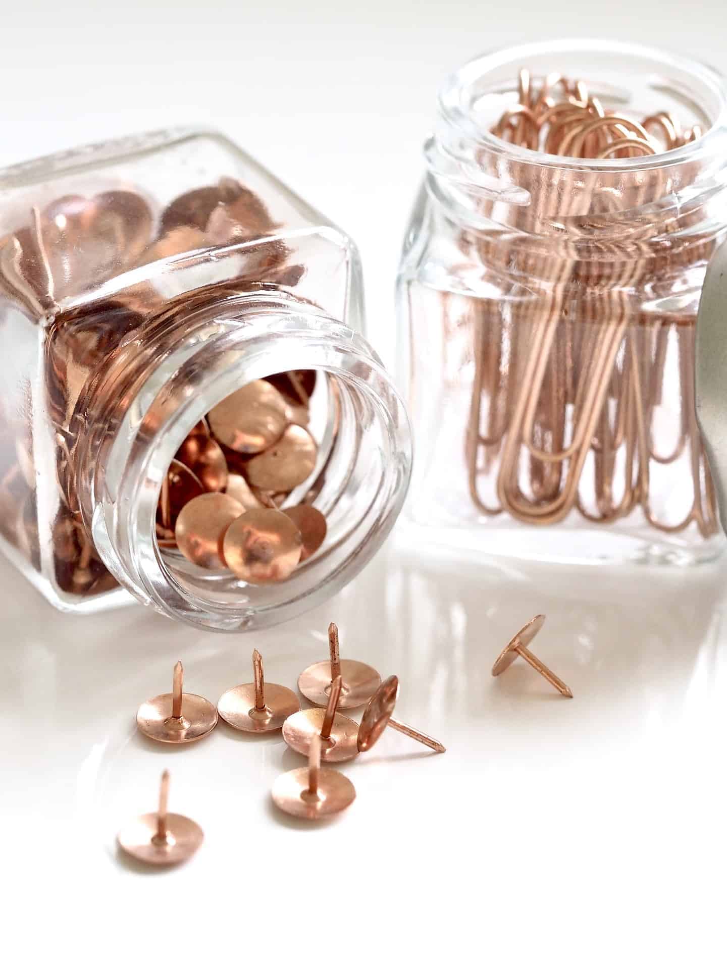 small jars holding tacks and paperclips on a desk for easy storages